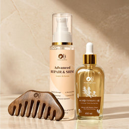 Three hair care products and a wooden hair comb arranged on a light beige marble surface: an Advanced Repair & Shine leave-in serum bottle, a Scalp Restore Oil dropper bottle, and a dark brown wooden comb with the Oli logo.